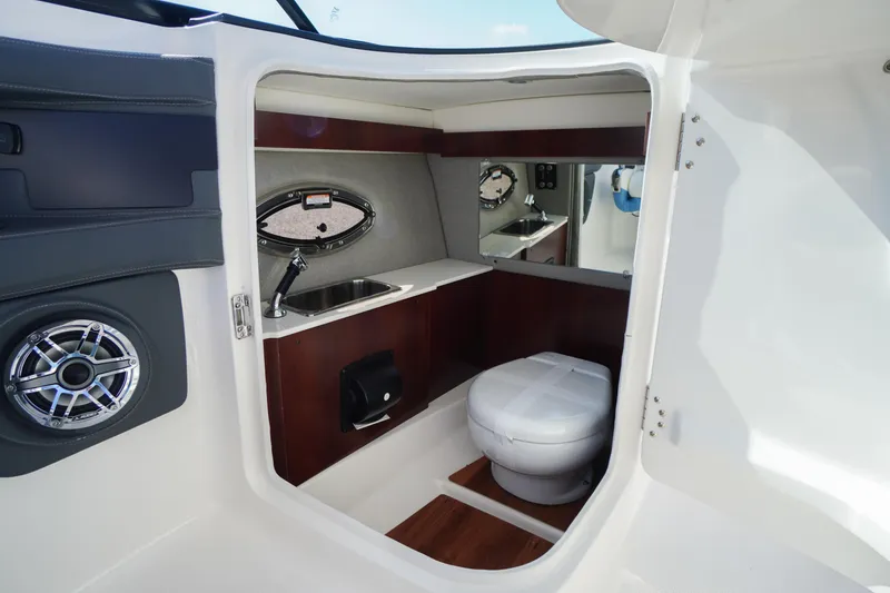 Slide: The Image of Interior of 2026 Chaparral 270 OSX boat featuring a compact bathroom with sink and toilet. - 32