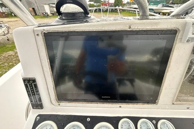 Slide: The Image of 1999 Donzi boat dashboard with Garmin display and gauges, wet from rain. - 30