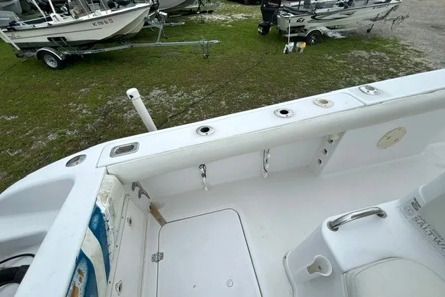 Slide: The Image of 1999 Donzi boat interior with rod holders, white seating, and nearby trailers on grass. - 35