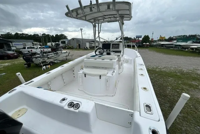Slide: The Image of 1999 Donzi boat with open deck, steering console, and T-top, parked outdoors. - 13