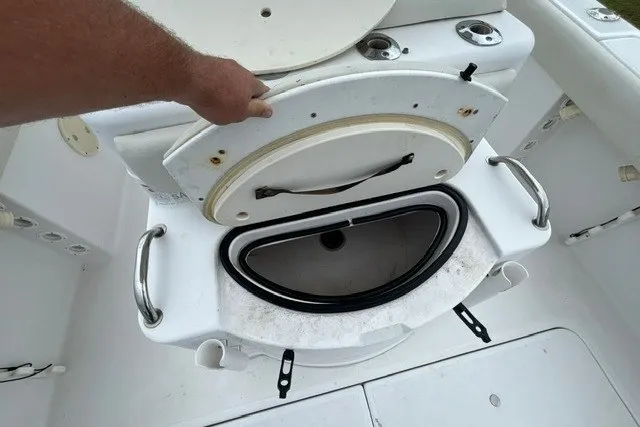 Slide: The Image of 1999 Donzi boat interior with open storage compartment and hand holding lid. - 34
