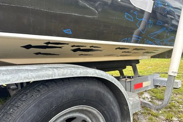 Slide: The Image of 1999 Donzi boat on trailer with fish decals, parked on grass. - 6