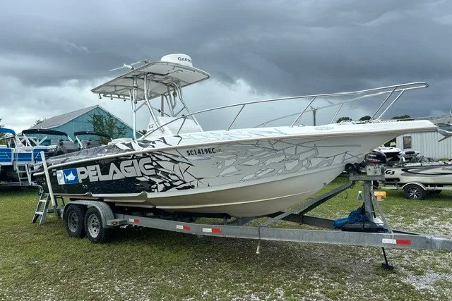 Slide: The Image of 1999 Donzi boat on trailer with Pelagic branding, parked outdoors under cloudy skies. - 49