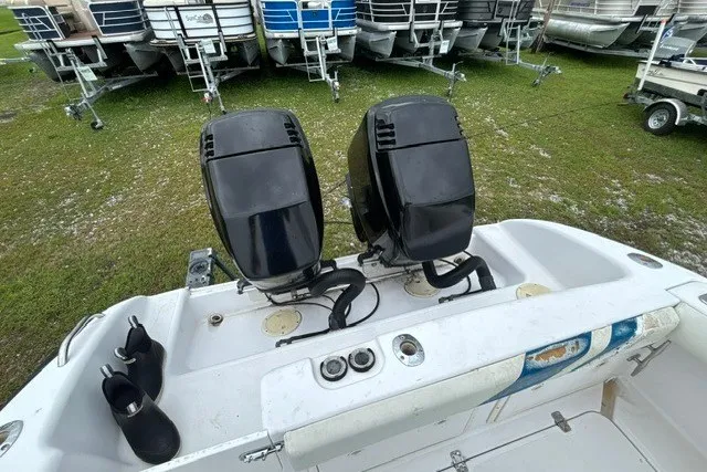Slide: The Image of 1999 Donzi boat with dual outboard motors, parked on grass near trailers. - 14