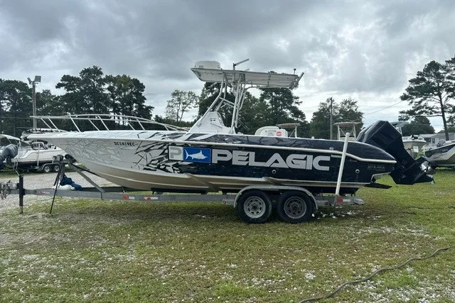Slide: The Image of 1999 Donzi boat on trailer with Pelagic branding, parked outdoors under cloudy skies. - 5