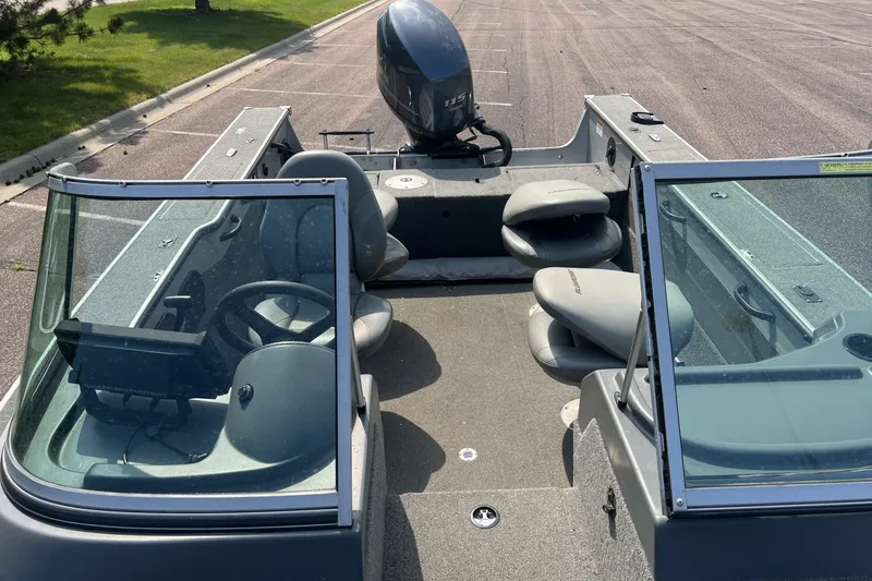 Slide: The Image of 2012 Alumacraft Trophy 175 boat with seating and windshield, parked on pavement. - 4