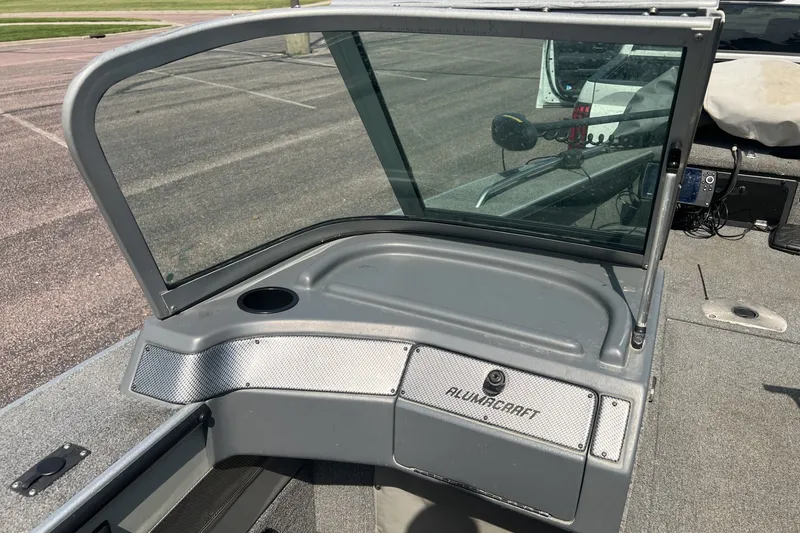 Slide: The Image of 2012 Alumacraft Trophy 175 boat windshield and dashboard in a parking lot. - 7