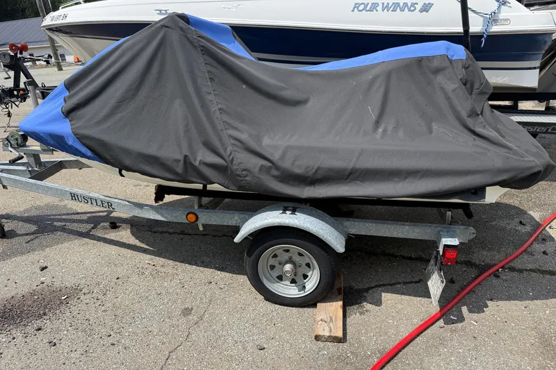 Slide: The Image of Covered 2005 Honda Aquatrax F-12 on trailer, parked beside a boat. - 10
