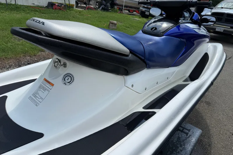 Slide: The Image of 2005 Honda Aquatrax F-12 jet ski with blue and white design, parked outdoors. - 5