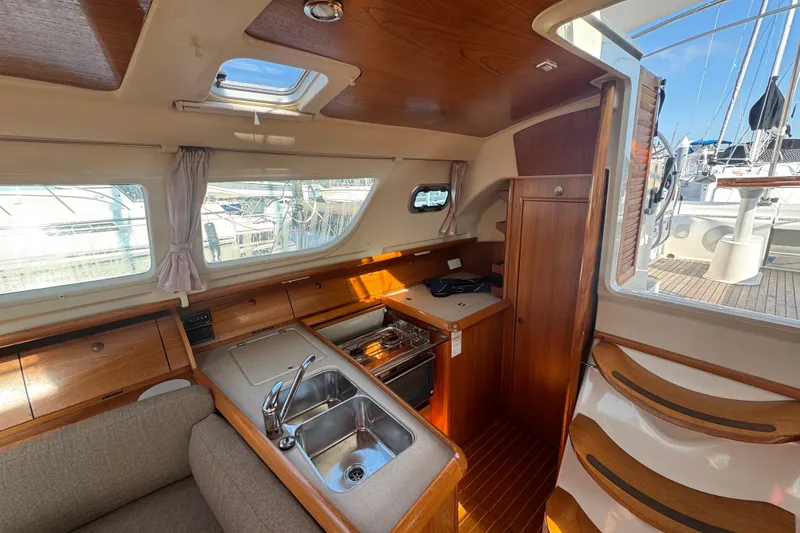 Slide: The Image of Interior of 1999 Jeanneau Sun Odyssey 40 DS sailboat, featuring a compact kitchen and wooden cabinetry. - 13