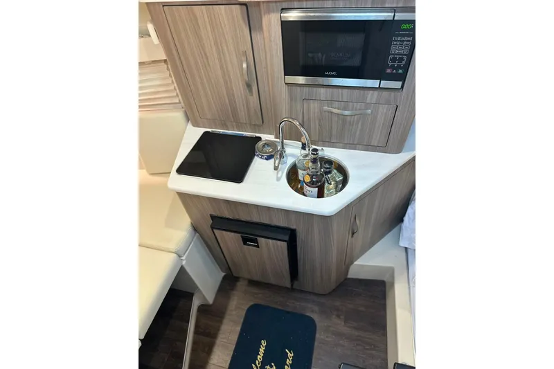 Slide: The Image of 2021 Regal 28 Express boat interior kitchenette with sink, stove, and microwave. - 44