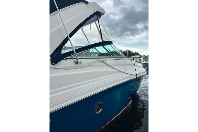 Slide: The Image of 2021 Regal 28 Express boat docked, featuring sleek white and blue design under cloudy skies. - 5