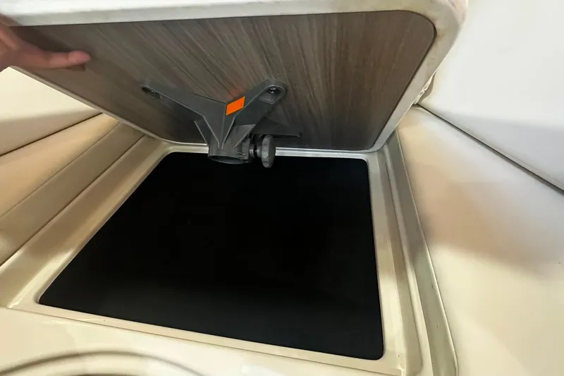 Slide: The Image of Storage compartment in a 2021 Regal 28 Express boat, featuring a hinged lid and black interior. - 34
