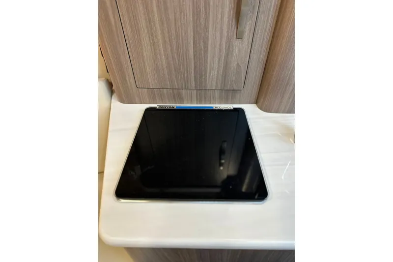 Slide: The Image of Built-in Kenyon cooktop on 2021 Regal 28 Express boat, featuring sleek wood cabinetry. - 19