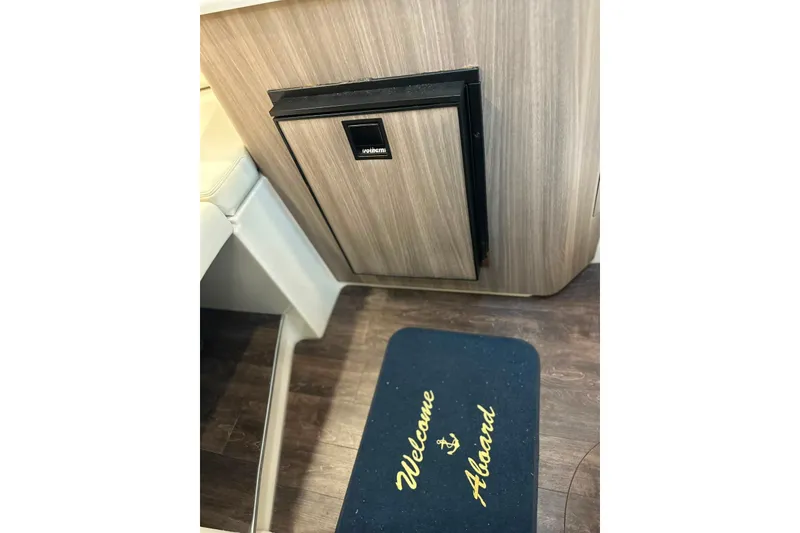 Slide: The Image of Interior of 2021 Regal 28 Express boat with fridge and welcome mat. - 24