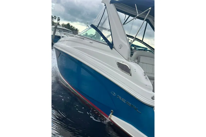 Slide: The Image of 2021 Regal 28 Express boat with blue hull, docked on water. - 36