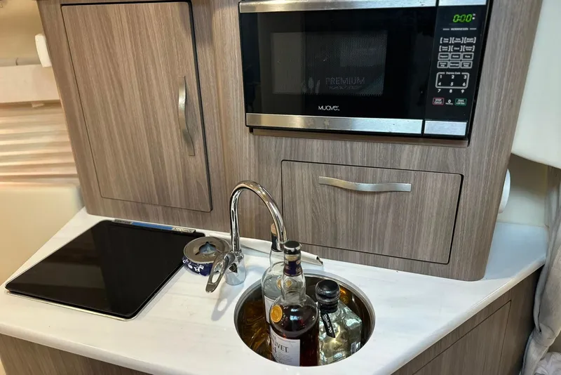 Slide: The Image of Compact kitchen area in a 2021 Regal 28 Express boat with microwave and sink. - 8