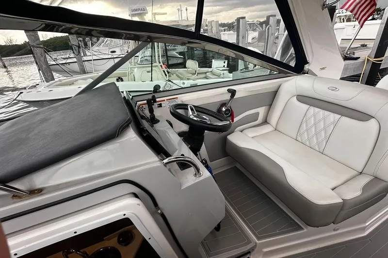 Slide: The Image of 2021 Regal 28 Express boat interior with steering wheel and seating at a marina. - 9