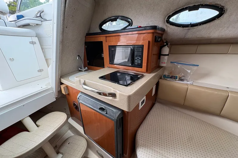Slide: The Image of Compact kitchen area in a 2003 Wellcraft 270 Coastal I/O boat, featuring a microwave and sink. - 10