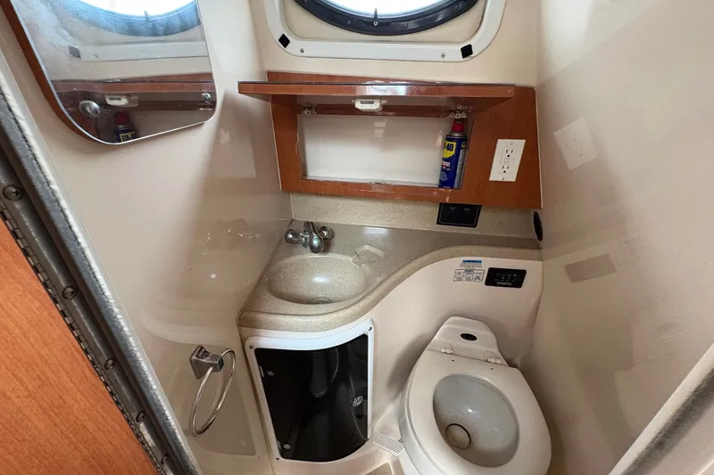 Slide: The Image of 2003 Wellcraft 270 Coastal I/O boat bathroom with sink, toilet, and storage cabinet. - 14