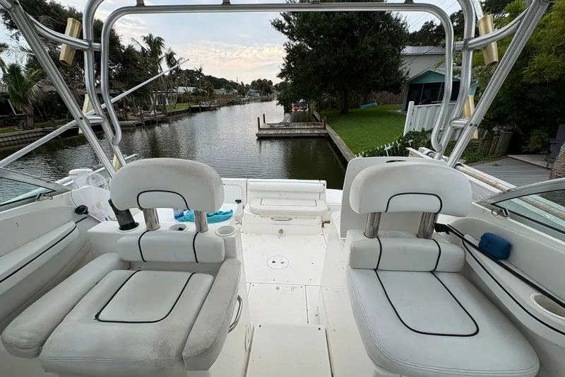 Slide: The Image of 2003 Wellcraft 270 Coastal I/O boat interior with white seating, overlooking a serene canal. - 5
