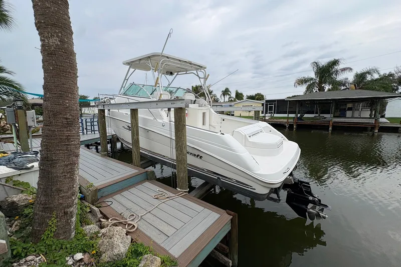 Slide: The Image of 2003 Wellcraft 270 Coastal I/O boat docked by a waterfront home with palm trees. - 2
