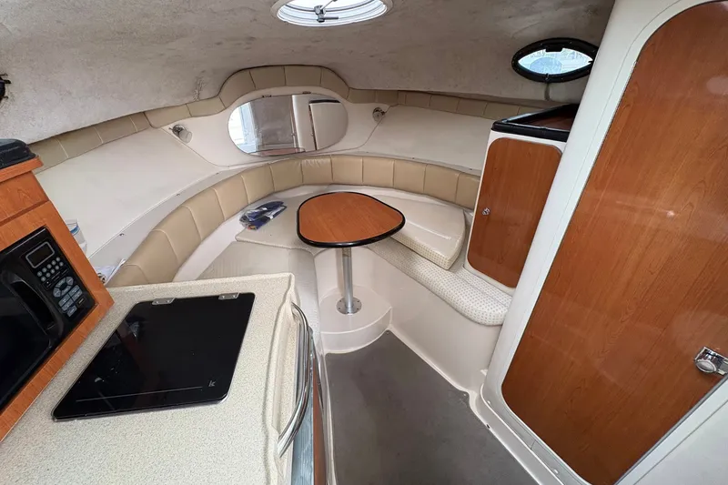 Slide: The Image of 2003 Wellcraft 270 Coastal I/O cabin interior with kitchenette, seating, and table. - 9