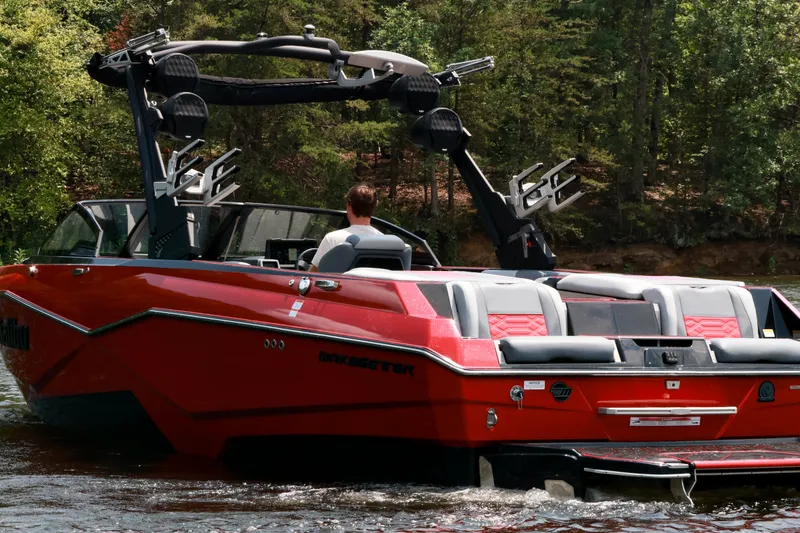 Slide: The Image of 2023 Malibu Wakesetter 25 LSV boat cruising on a lake with lush greenery. - 3