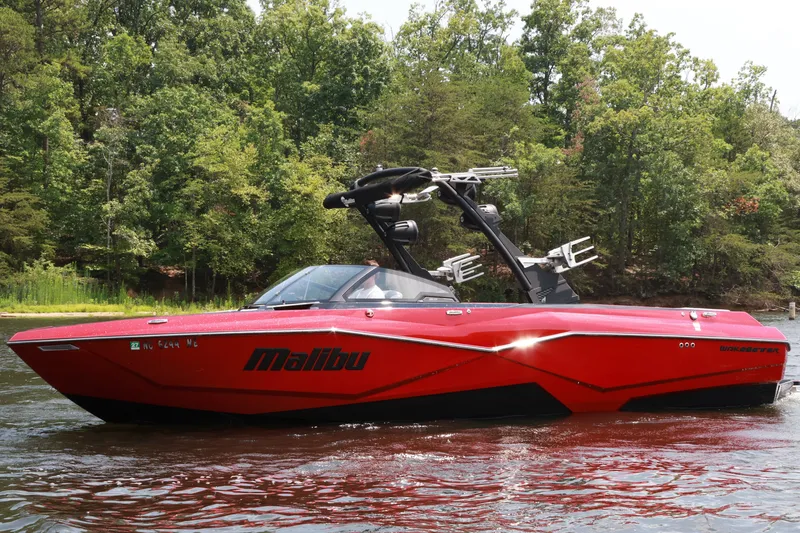 Slide: The Image of 2023 Malibu Wakesetter 25 LSV boat in vibrant red on a serene lake. - 2