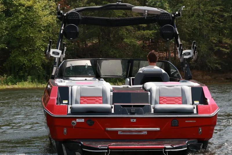Slide: The Image of 2023 Malibu Wakesetter 25 LSV boat on water, rear view with lush greenery. - 4