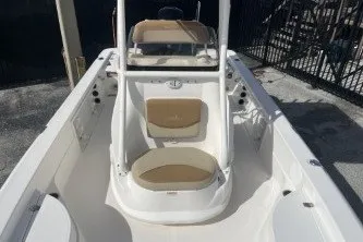 Slide: The Image of 2023 NauticStar 227 XTS boat interior with seating and console, docked outdoors. - 11