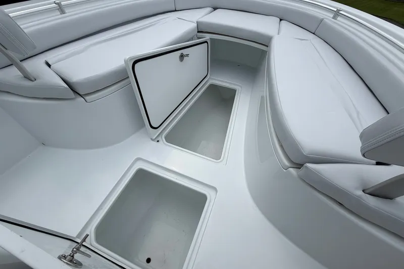 Slide: The Image of 2027 Contender 24 Sport boat interior with open storage compartments and cushioned seating. - 6