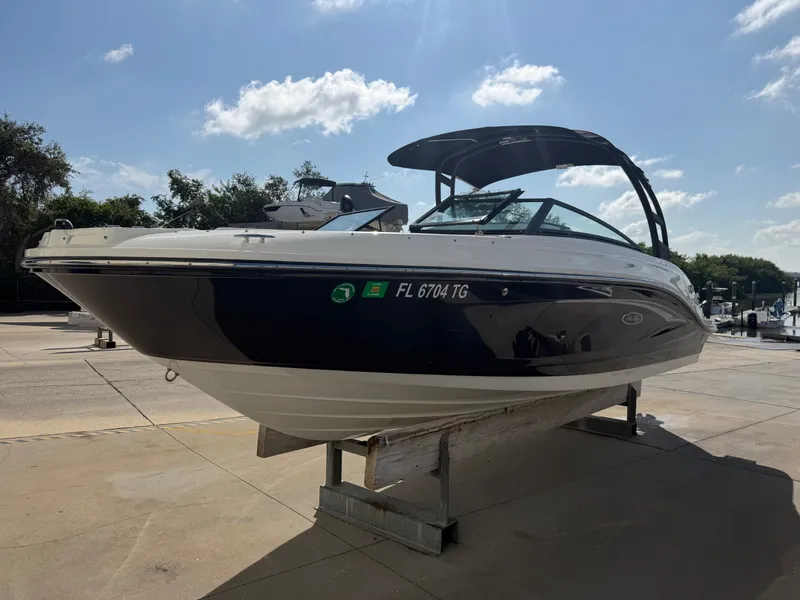 Slide: The Image of A 2022 Sea Ray SPX 230 Outboard is on a dock. It features a sleek design and black hull. - 1