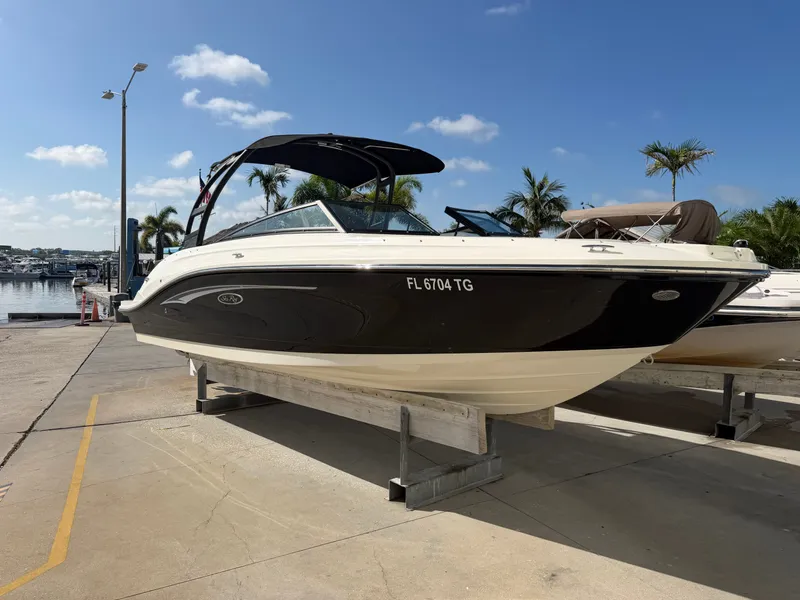 Slide: The Image of A 2022 Sea Ray SPX 230 Outboard is on a dock. Palms and boats are in the background. - 0