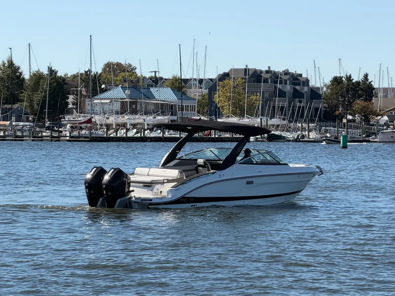 Slide: The Image of A 2027 Sea Ray SLX 280 Outboard cruising on calm waters with a marina in the background. - 6