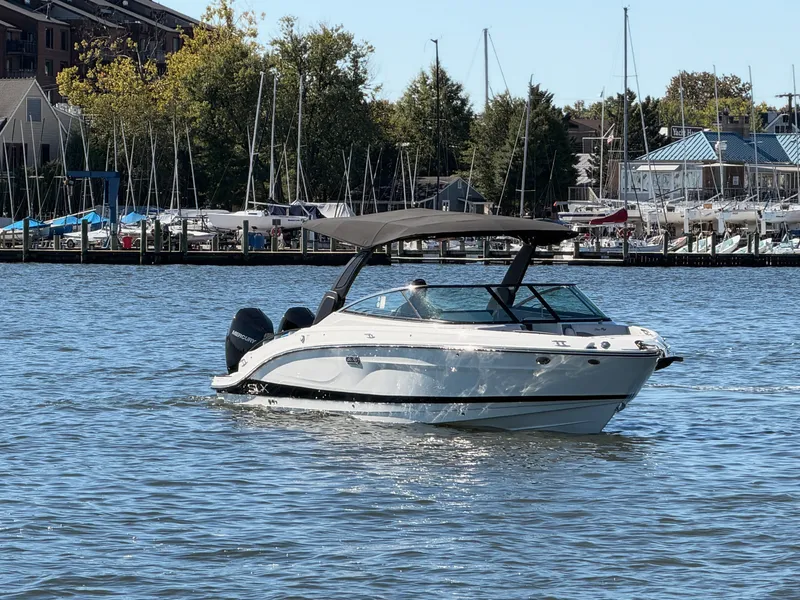 Slide: The Image of A 2027 Sea Ray SLX 280 Outboard cruising on calm waters with a marina in the background. - 1