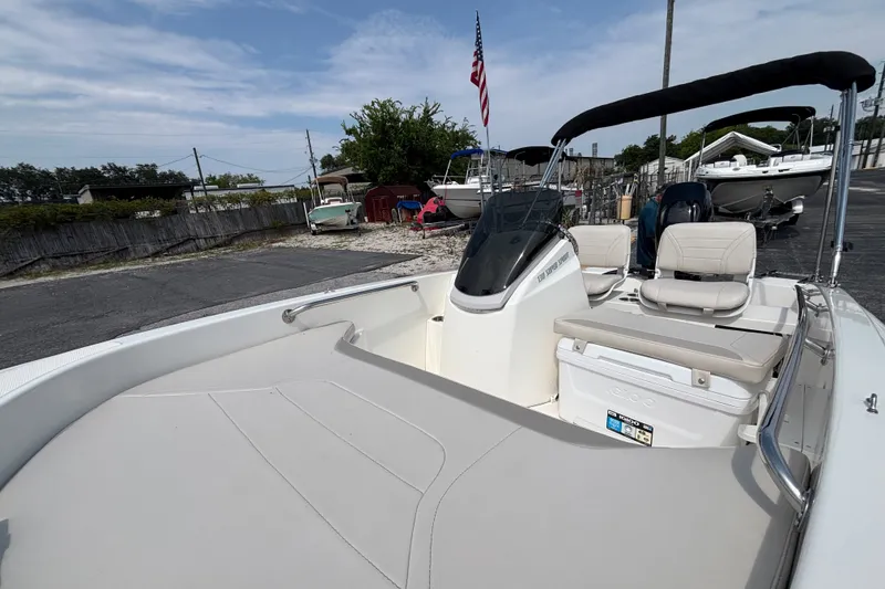 Slide: The Image of 2025 Boston Whaler 130 Super Sport boat with seating, docked under a clear sky. - 24