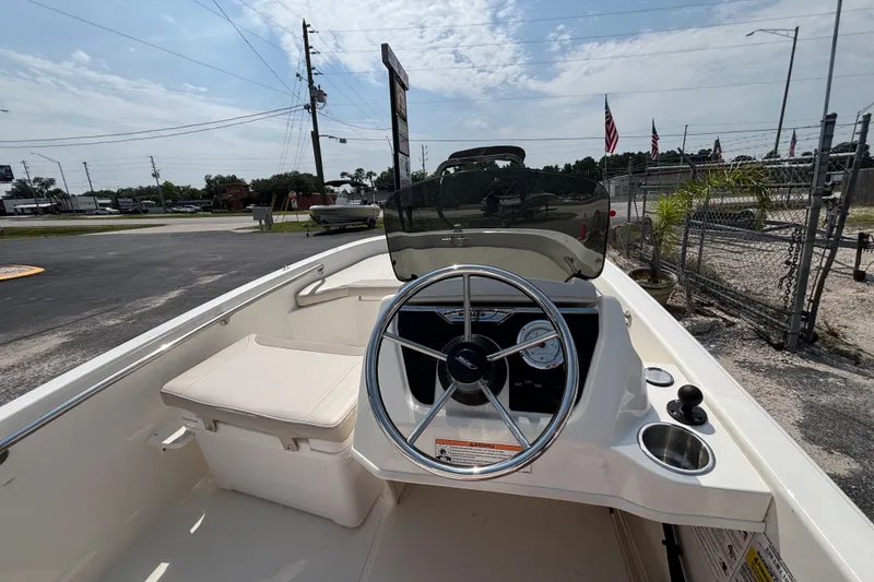 Slide: The Image of 2025 Boston Whaler 130 Super Sport boat interior with steering wheel and seating. - 18