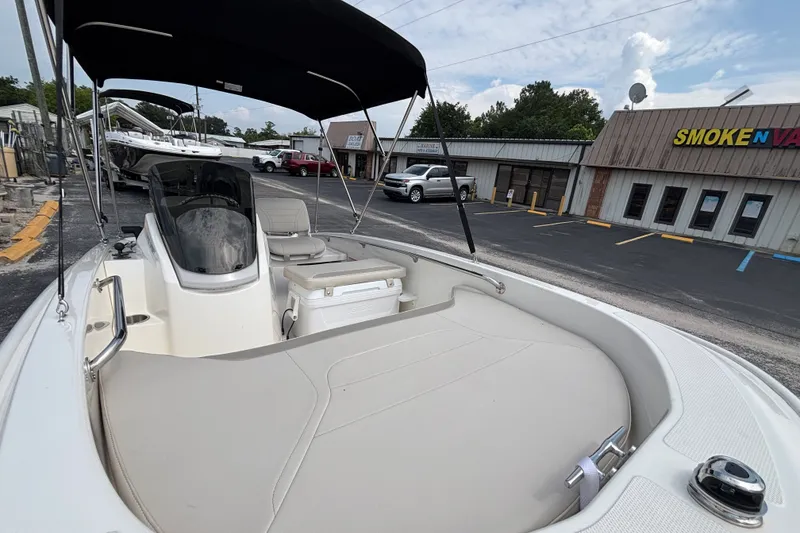 Slide: The Image of 2025 Boston Whaler 130 Super Sport boat with canopy, parked near a storefront. - 31