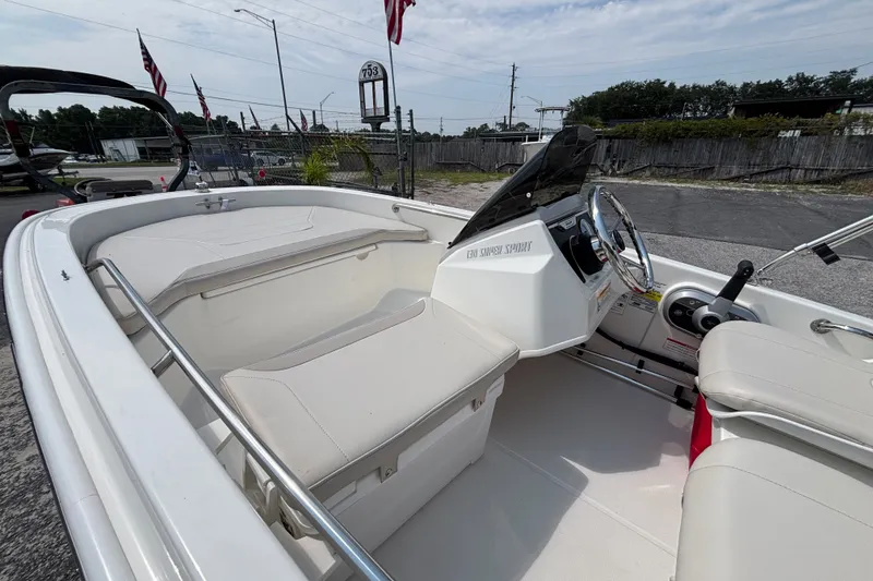 Slide: The Image of 2025 Boston Whaler 130 Super Sport boat interior with steering wheel and seating. - 23