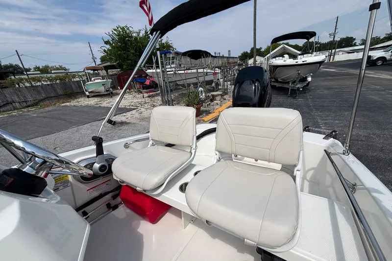 Slide: The Image of 2025 Boston Whaler 130 Super Sport boat interior with dual white seats and steering console. - 26