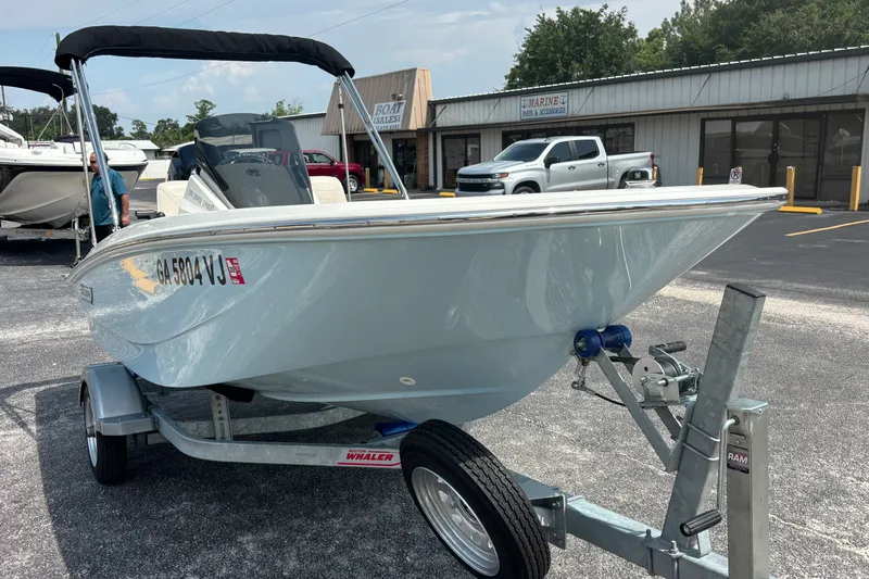 Slide: The Image of 2025 Boston Whaler 130 Super Sport boat on trailer in parking lot. - 21