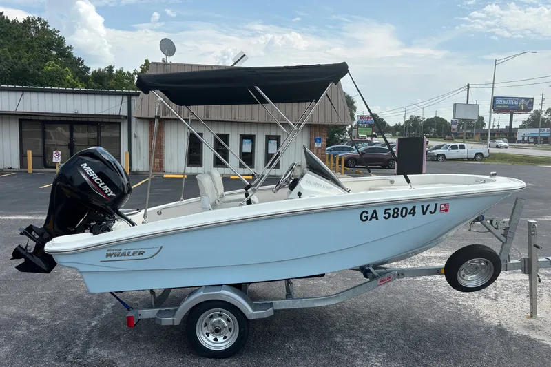 Slide: The Image of 2025 Boston Whaler 130 Super Sport boat on trailer, parked outdoors. - 6