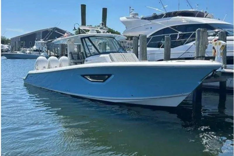 The Image of 2023 Pursuit S 378 Sport boat docked in marina, featuring sleek blue hull design. - 0