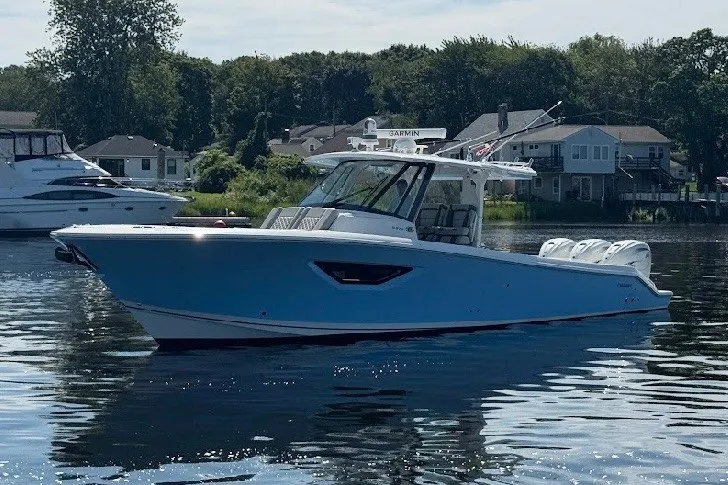 The Image of 2023 Pursuit S 378 Sport boat on calm water, with houses and trees in the background. - 0