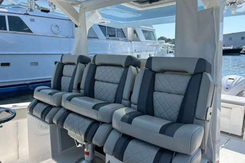 Slide: The Image of 2023 Pursuit S 378 Sport boat with luxurious seating, docked near other yachts. - 15