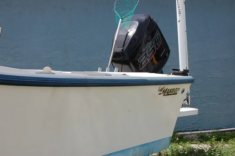 Slide: The Image of 1992 Mako 221 Center Console boat with outboard motor, docked near a blue wall. - 3