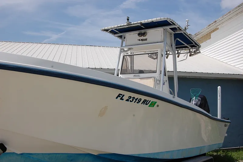Slide: The Image of 1992 Mako 221 Center Console boat with registration FL 2319 RU, docked near a building. - 2