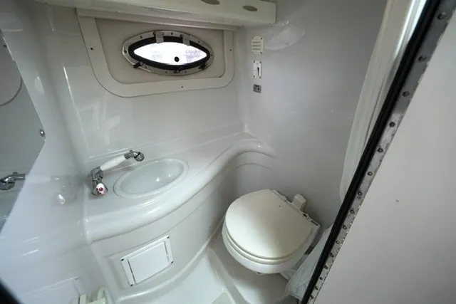 Slide: The Image of 2008 Crownline 250 CR boat bathroom with sink, toilet, and porthole window. - 19