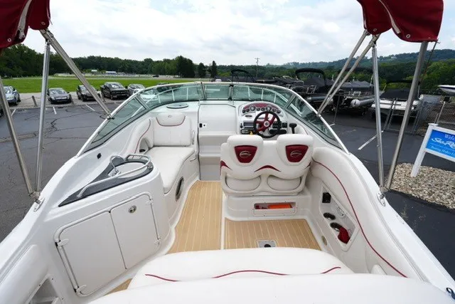 Slide: The Image of 2008 Crownline 250 CR boat interior with white seating and red accents, docked outdoors. - 8